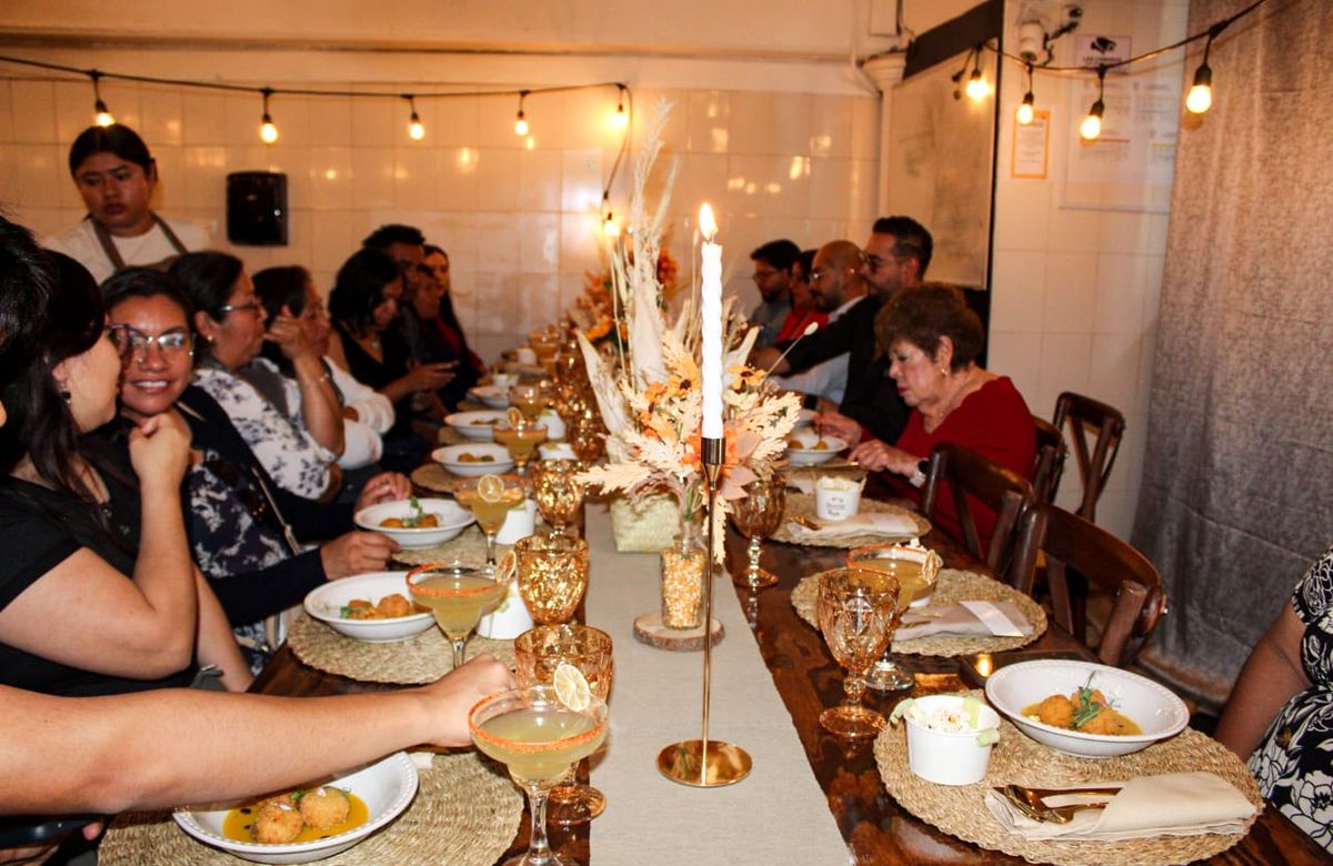 Invitados reunidos alrededor de una mesa larga con sillas crossback