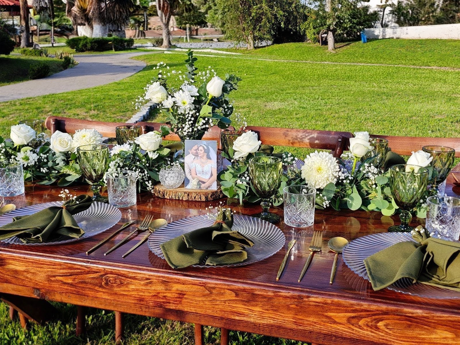Montaje de mesa verde y blanco con vajilla, cristalería y flores