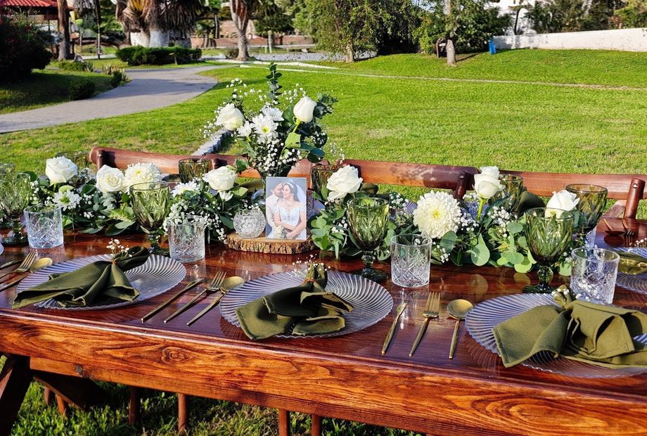 Mesa al aire libre con flores blancas, follaje y fotografías personales