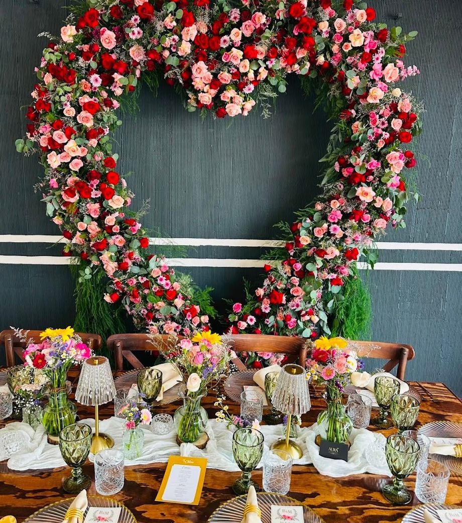 Mesa preparada frente a un arco floral para una celebración especial