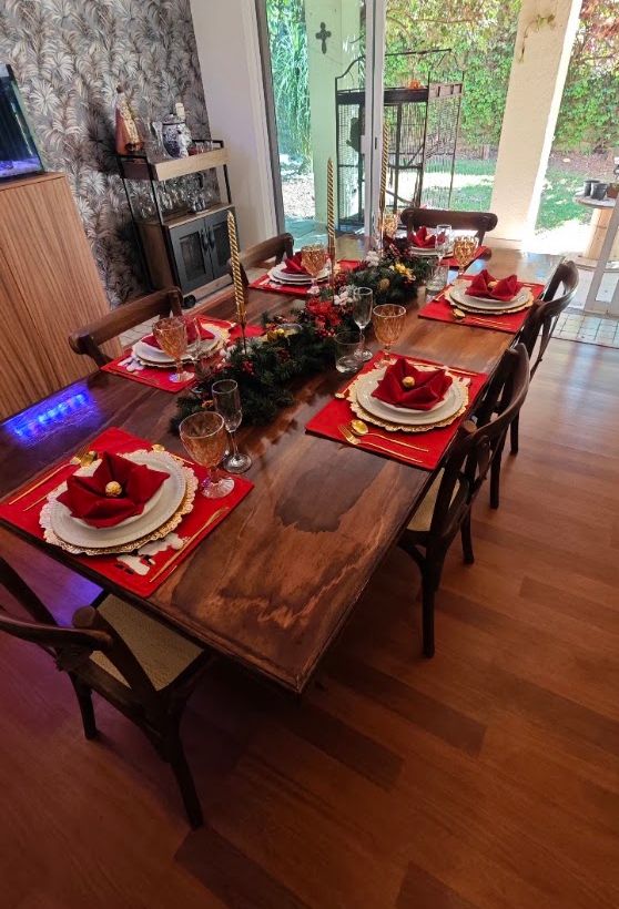 Mesa de madera preparada con flores rojas, velas y vajilla