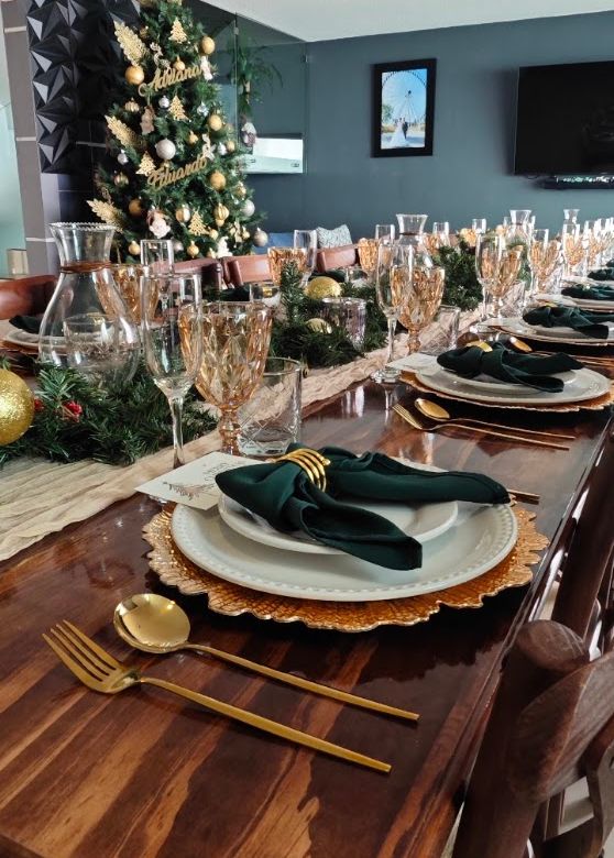Mesa con velas, follaje, cristalería ámbar y textiles verdes