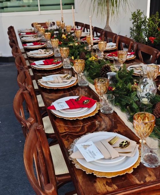 Mesa de madera preparada con velas, flores y cristalería para una celebración privada