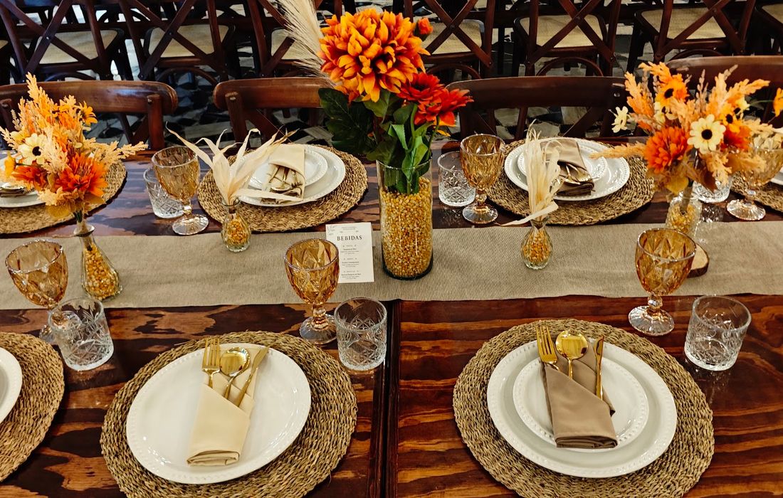 Montaje de mesa de madera con flores en tonos maíz y cristalería ámbar