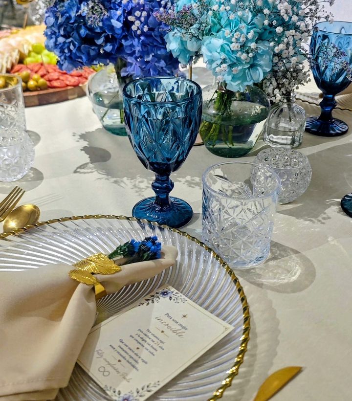 Mesa con flores azules, cristalería y velas blancas